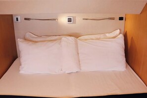 A bed with white bedding, a headboard with a light switch, and a wooden panel on the right. - Caribbean Dream: Sun-soaked Sailing Adventure from Tortola, Islas Vírgenes Británicas (Road Town)