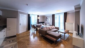 Moderni hotellihuone, jossa on sohva, ruokapöytä ja keittiöalue.