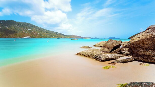A beach with clear turquoise water, large rocks, and distant boats. - Sun-Kissed Sailing: A Caribbean Beach Experience from Islas Vírgenes de Estados Unidos, Santo Tomás (St Thomas)