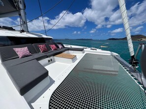 Ein Bootsdeck mit Sitzgelegenheit, Grill und Blick auf das Meer und Inseln.
