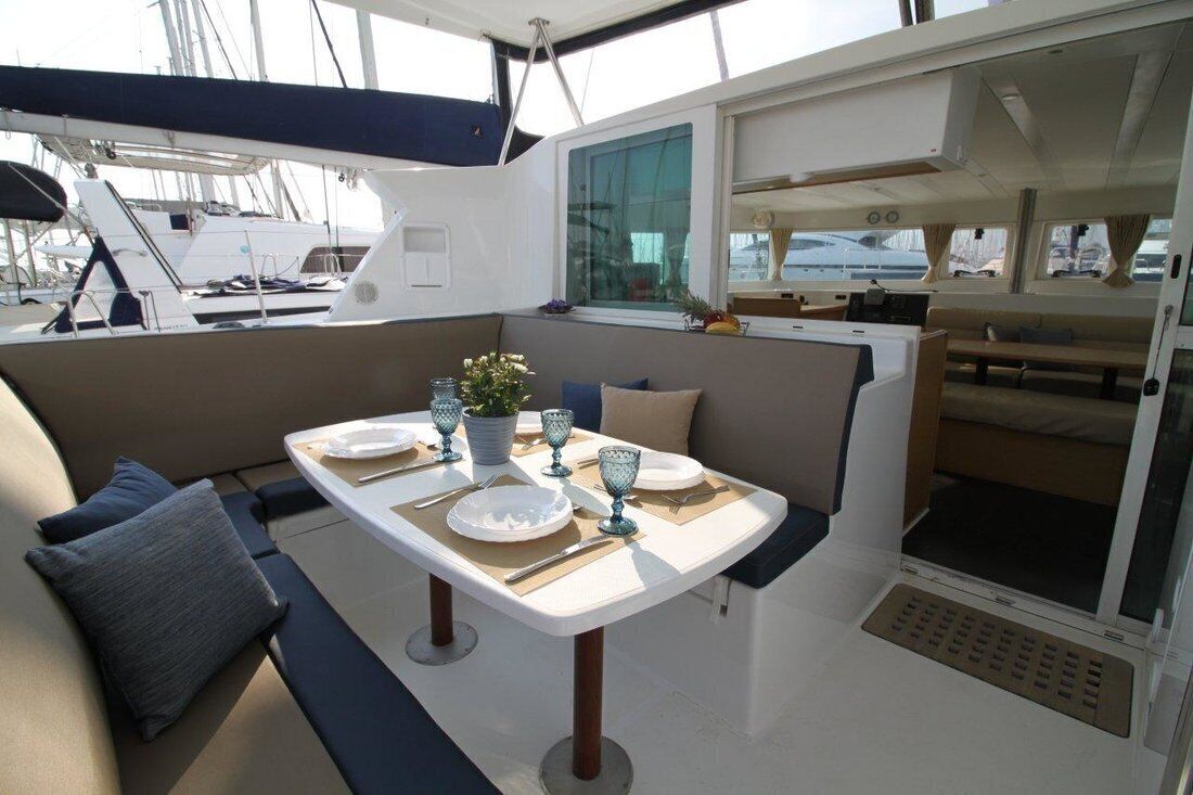 A boat interior with a dining area, seating, and a window.