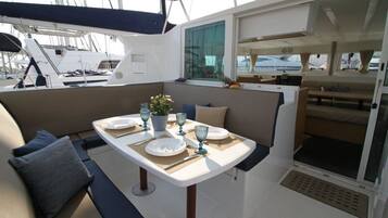 A boat interior with a dining area, seating, and a window.