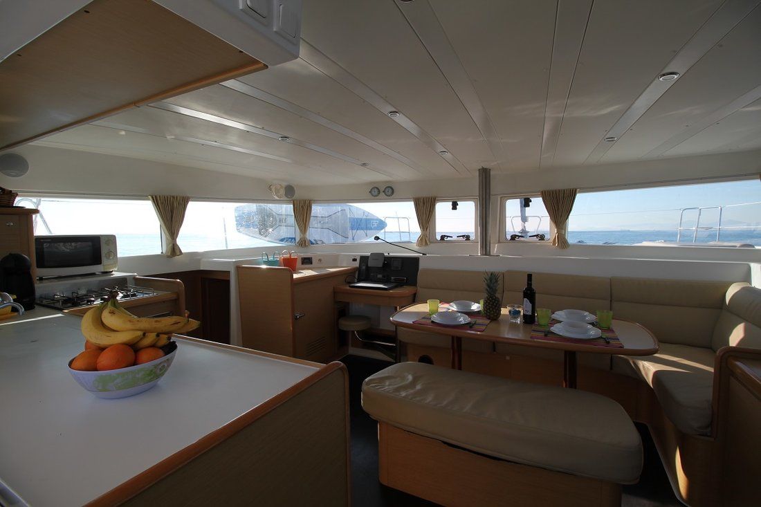 A compact galley with a stove, a small sink, a dining area with a table and chairs, and a seating area with a cushioned bench.