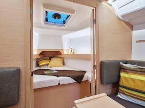 Ein kompaktes Wohnmobil-Interieur mit Etagenbett, Dachfenster und einer kleinen Küchenzeile.