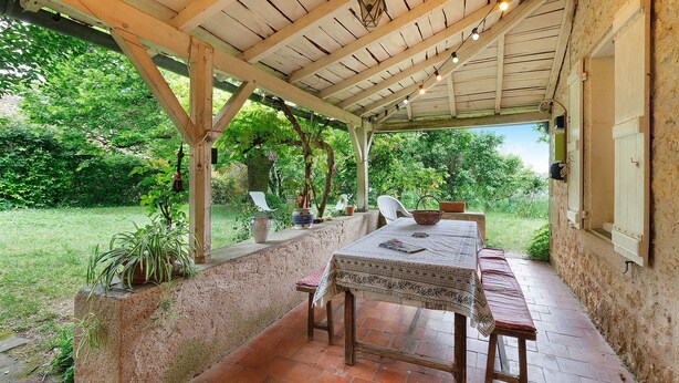 Eine Terrassengruppe mit Tisch und Bänken, umgeben von viel Grün.