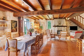 Ein rustikaler Essbereich mit Holztischen, einem Fliesenboden und einer Steinwand.