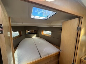 A compact, well-lit interior with a bunk bed, skylight, and storage compartments.