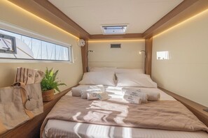 A compact hotel room with a bed, a window, a ceiling fan, and a small plant. - Sun-Kissed Sailing Adventure in the Ionian Islands, Lefkada (Lefkada)
