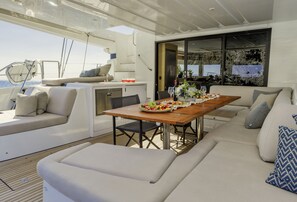 A yacht interior with a dining area, seating, and a view of the sea. - Sun-Kissed Sailing Adventure in the Saronic Islands (Elliniko)