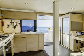 A modern kitchen with a view of the sea, a dining area, and a small office space. - Sun-Kissed Sailing Adventure in the Saronic Islands (Elliniko)