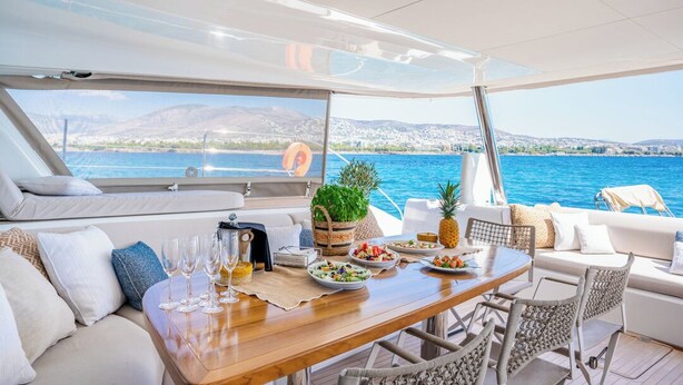 A yacht interior with a dining area, seating, and a view of the sea. - Sun-Kissed Sailing Adventure in the Saronic Islands (Elliniko)