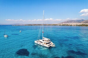 Une mer d’un bleu profond, avec un voilier et un plus petit bateau.