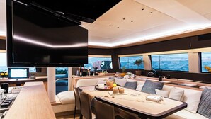 A modern interior with a dining area, kitchen, and large windows offering ocean views. - Sun-Kissed Sailing Adventure in the Saronic Islands (Elliniko)