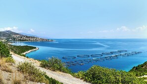 Eine Küstenlandschaft mit freiem Blick auf das Meer, einer Straße und einer in der Ferne liegenden Stadt.