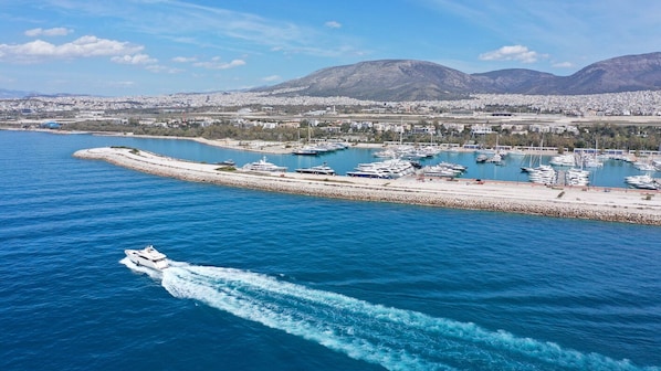 Un port de plaisance avec des bateaux, une plage de sable et un paysage urbain avec des montagnes en arriĂšre-plan.
