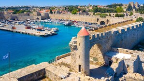 A historic stone fortress with a tower, a harbor with boats, and a clear blue sky. - Sun-Kissed Sailing Adventure in the Dodecanese Islands (Rodos)