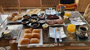 Ein Esstisch mit Gebäck, Brot und Getränken, mit Blick auf einen Pool.