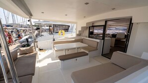 L’intérieur d’un yacht comprenant un coin salon, une table et une vue sur le port de plaisance.