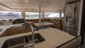 Une cuisine moderne équipée d’un réfrigérateur en acier inoxydable, d’un évier et d’un coin repas offrant une vue sur le port.