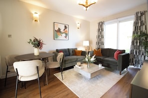 A modern living room with a sofa, coffee table, and dining area. - Presented by Aurora Short Stays! This spacious 2-bedroom property at Albion St, Motherwell is perfectly located near shops, cafés, and everyday amenities. Sleeping up to 4 guests, it features 1 king bed and 2 single beds for a comfortable stay. (North Lanarkshire)