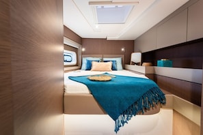 A bedroom with a skylight, a bed with a blue blanket, and a bedside table with decorative items.