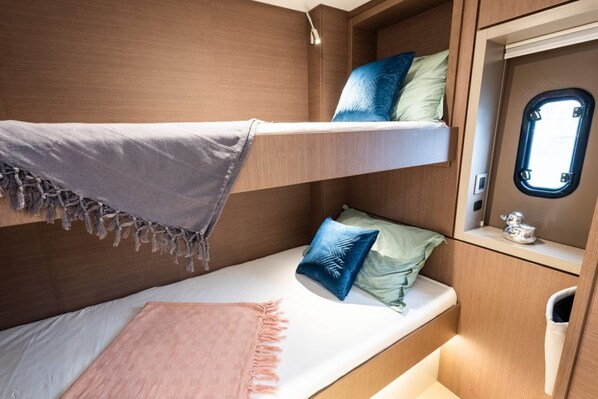 A bunk bed with a window, a small shelf with a decorative item, and a light fixture.