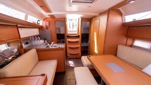 A compact RV interior with a kitchenette, seating area, and storage cabinets.