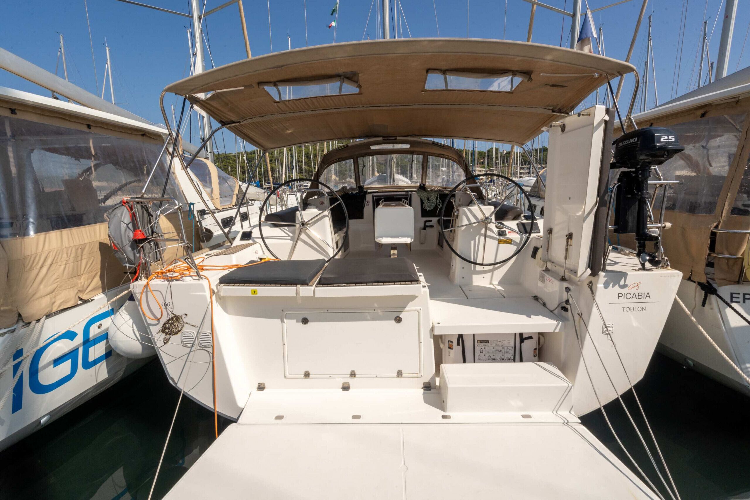 A boat's deck with a steering wheel, control panel, and seating area.