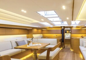 A yacht interior with a dining area, seating, and a kitchen.