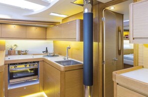 A compact kitchen with a built-in oven, a sink, and wooden cabinetry.