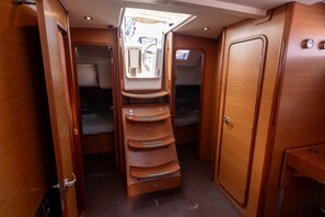Une cabine compacte et bien éclairée, dotée d’une étagère centrale, d’un lit et d’une armoire.