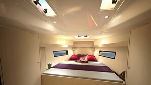 Ein kompakter, gut beleuchteter Raum mit einem Bett, einer kleinen Pflanze und zwei gerahmten Bildern an den Wänden.