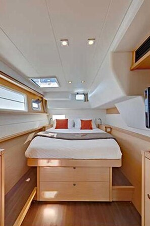 A narrow, compact cabin with a bed, a small window, and a built-in storage drawer.