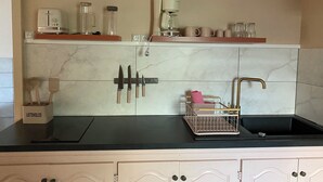 Een keuken met een marmeren achterwand, een messenblok, een koffiezetapparaat en een gootsteen met een handdoekhouder.