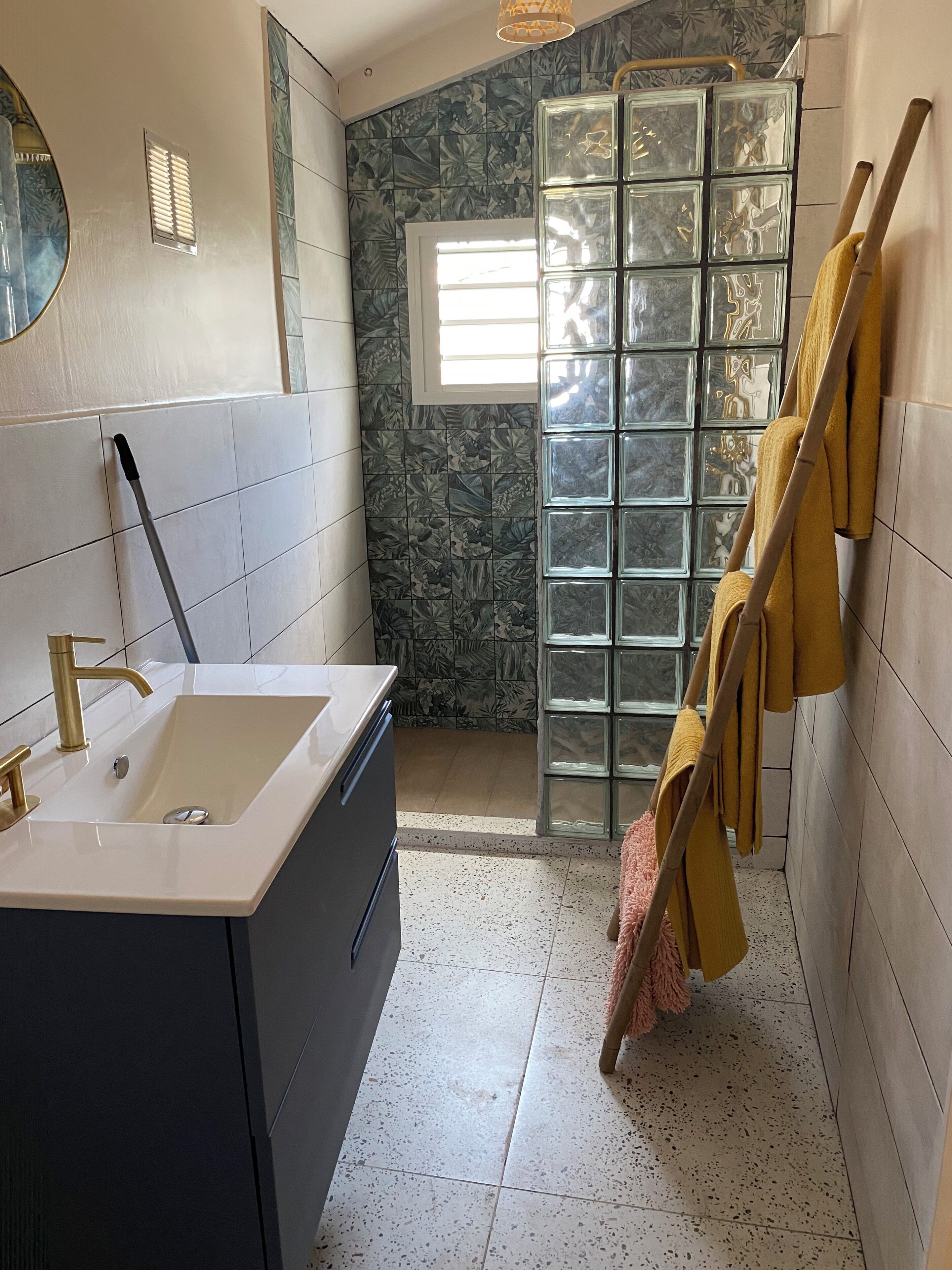 A bathroom with a large sink, a mirror, a shower with a glass door, and towels hanging on the wall.