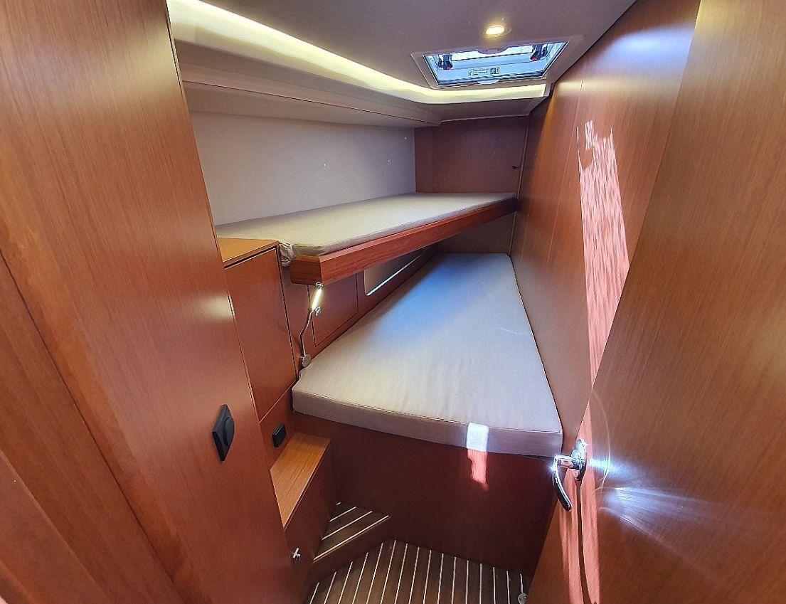 A compact interior with a bunk bed, a skylight, and a small seating area.