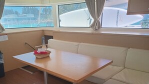 Een blokhut met een houten tafel, een rieten mand met rode bloemen, een fles en een wit kussenbankje.