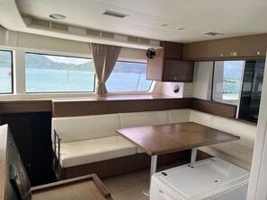 Una cocina compacta con una mesa de madera y bancos, un refrigerador pequeño y una ventana con vista al agua.