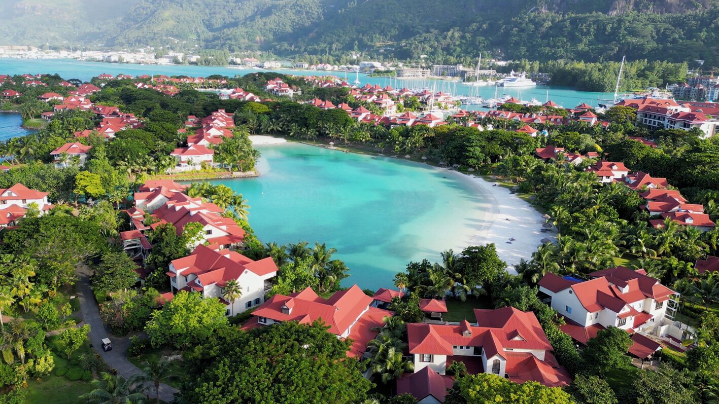 A coastal resort with red-roofed villas, a central lagoon, and a marina.
