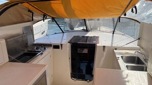 Une petite cuisine fonctionnelle, équipée d’une cuisinière, d’un évier et de placards de rangement, à bord d’un bateau.