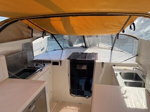 Une petite cuisine fonctionnelle, équipée d’une cuisinière, d’un évier et de placards de rangement, à bord d’un bateau.