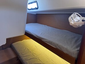 Un lit superposé avec une tête de lit, une fenêtre et un objet blanc sur le côté droit.