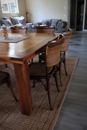 A dining area with a wooden table, wicker chairs, and a patterned rug.