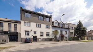 A multi-story residential building with a garage, a visible storefront, and a street view. - Cozy Apartment | Workspace (Kraków)
