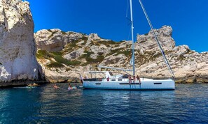 Un velero anclado cerca de una costa rocosa con aguas azules cristalinas.