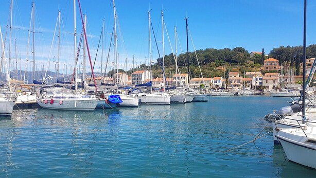 Un port de plaisance où sont amarrés de nombreux voiliers, entouré de bâtiments aux toits recouverts de tuiles rouges.