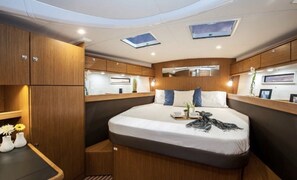 Une chambre à coucher compacte et bien éclairée, comprenant un lit, des tables de chevet et des armoires encastrées.