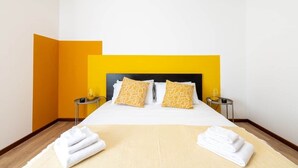 Habitación de hotel con una cama, dos almohadas, dos mesitas de noche y una colcha.