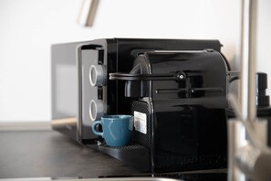 A black espresso machine with a blue cup on its drip tray.