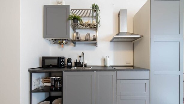 Una cocina moderna con armarios grises, un microondas, una cafetera y un fregadero.